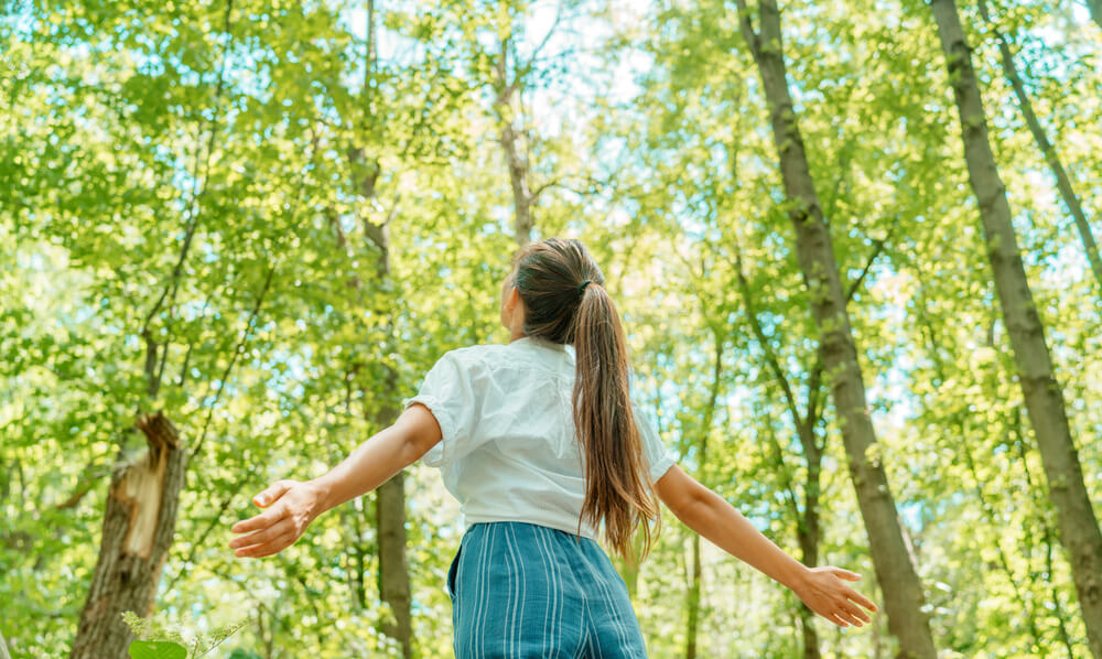 Woman breathing clean air in nature forest