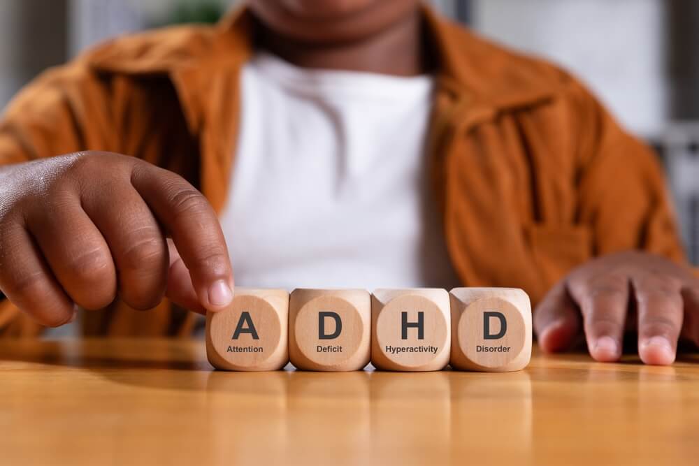 Hand of boy puts wooden cube with ADHD