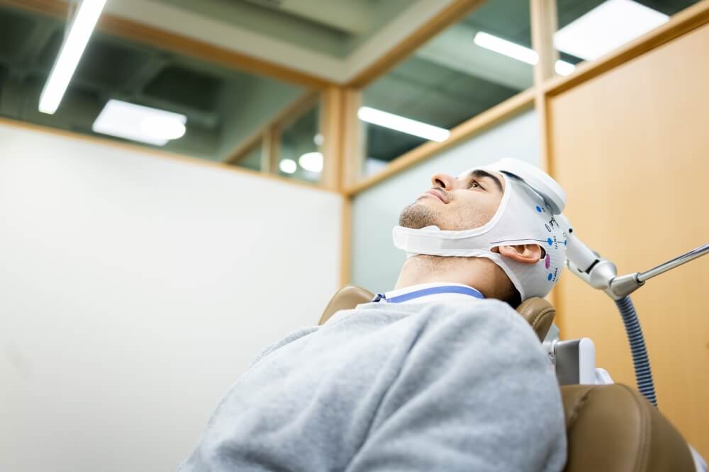 Man undergoes transcranial magnetic stimulation therapy in a psychiatric clinic