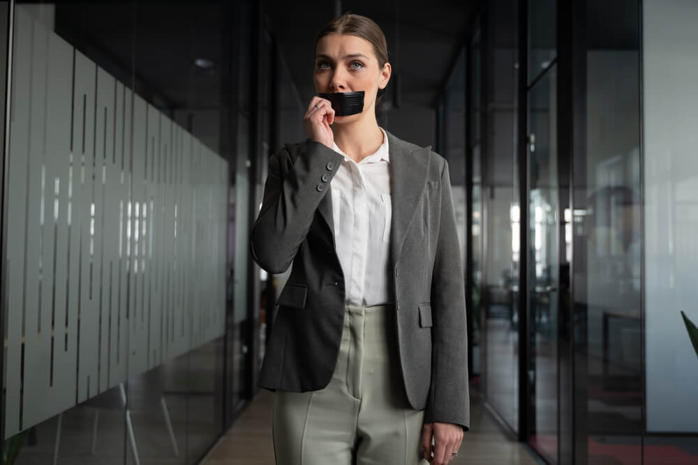 Professional woman in an office removing duct tape from her mouth