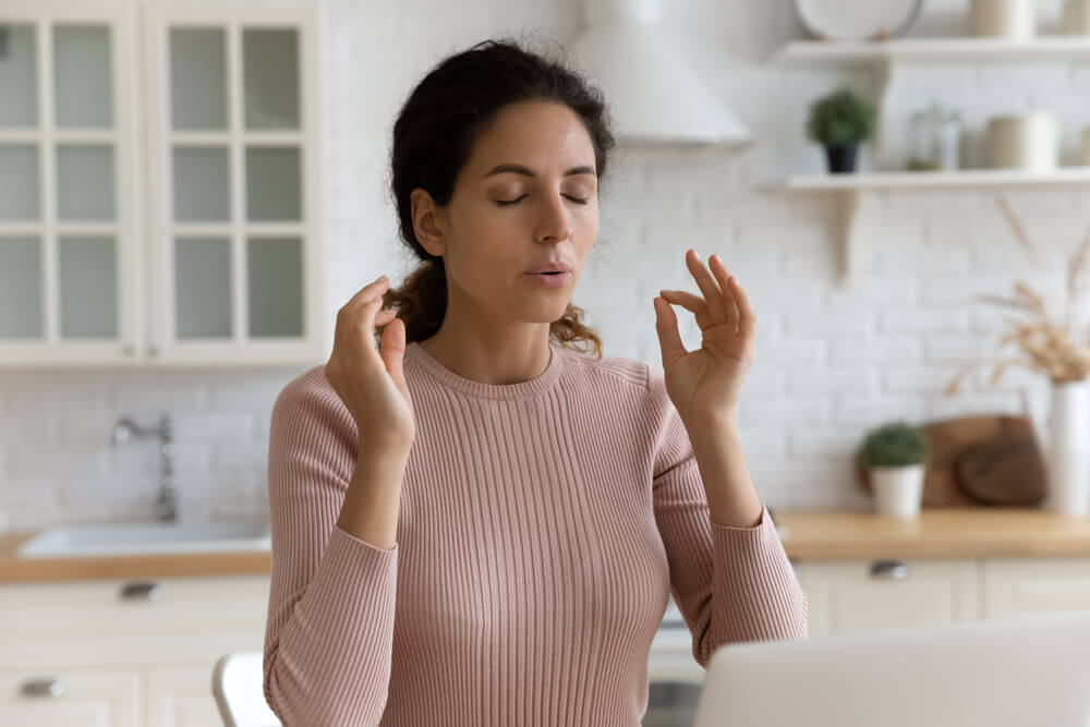 Mindful young woman breathing out with closed eyes
