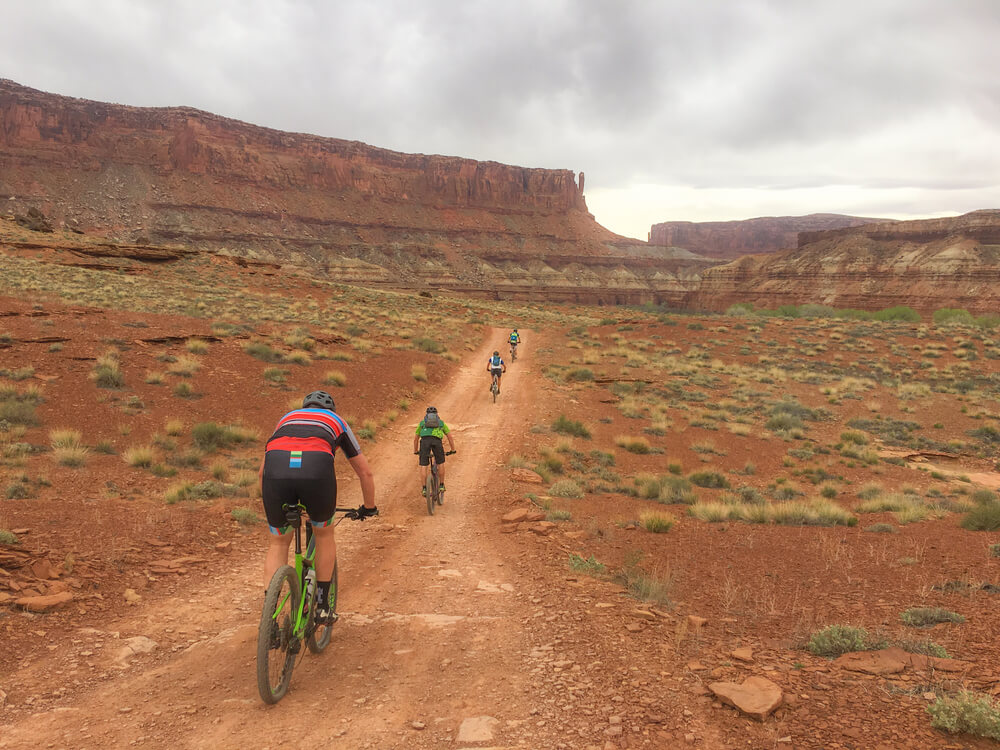 A group of cyclists travels the white rim trail