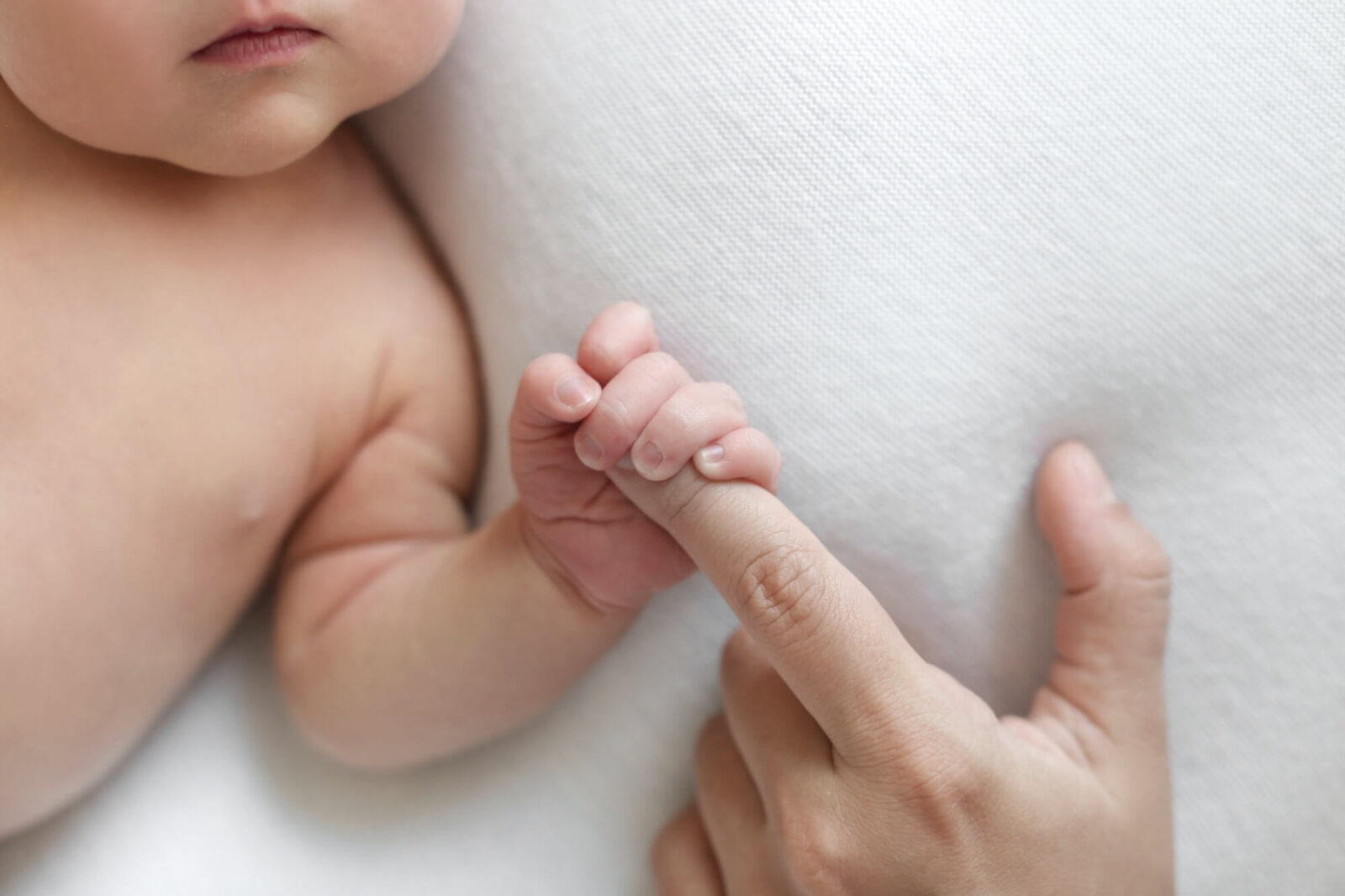 The newborn is holding a finger of mother