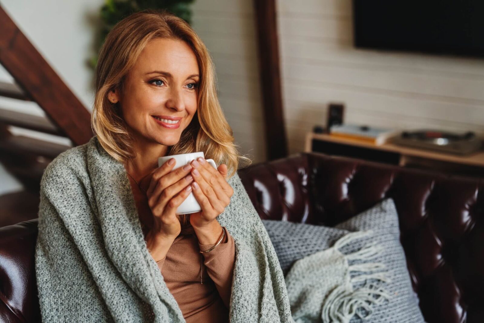 middle aged woman sitting in living room with cup of coffee