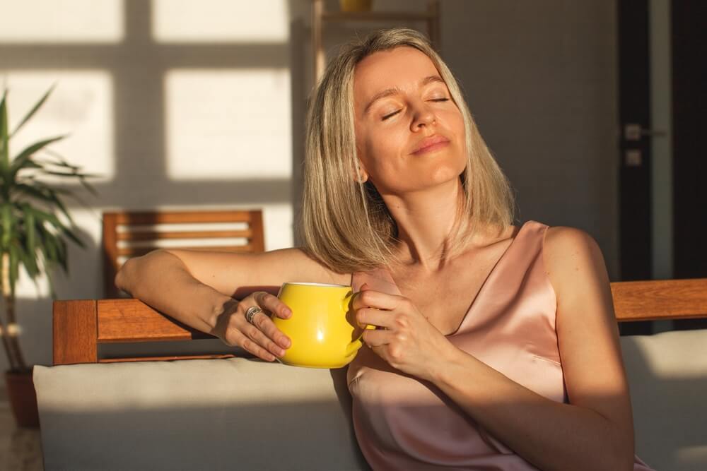 Attractive happy middle aged woman is sitting on sofa in living room