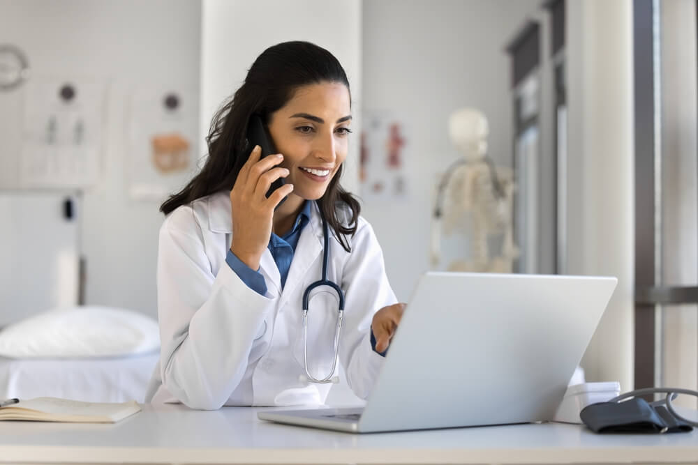 Young female doctor talking to patient on mobile phone