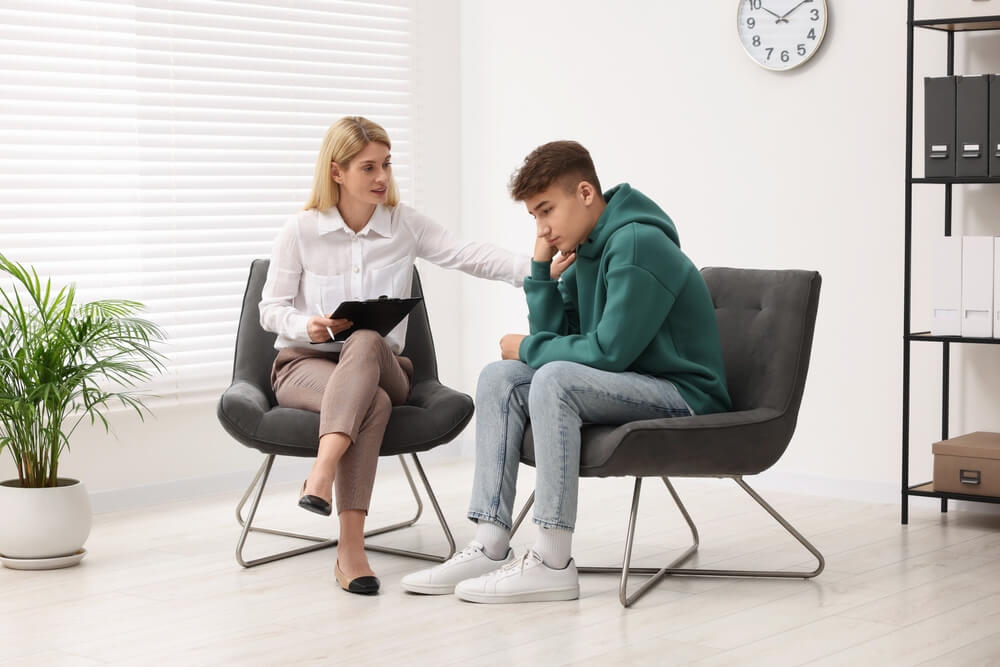 Psychologist working with teenage boy in office