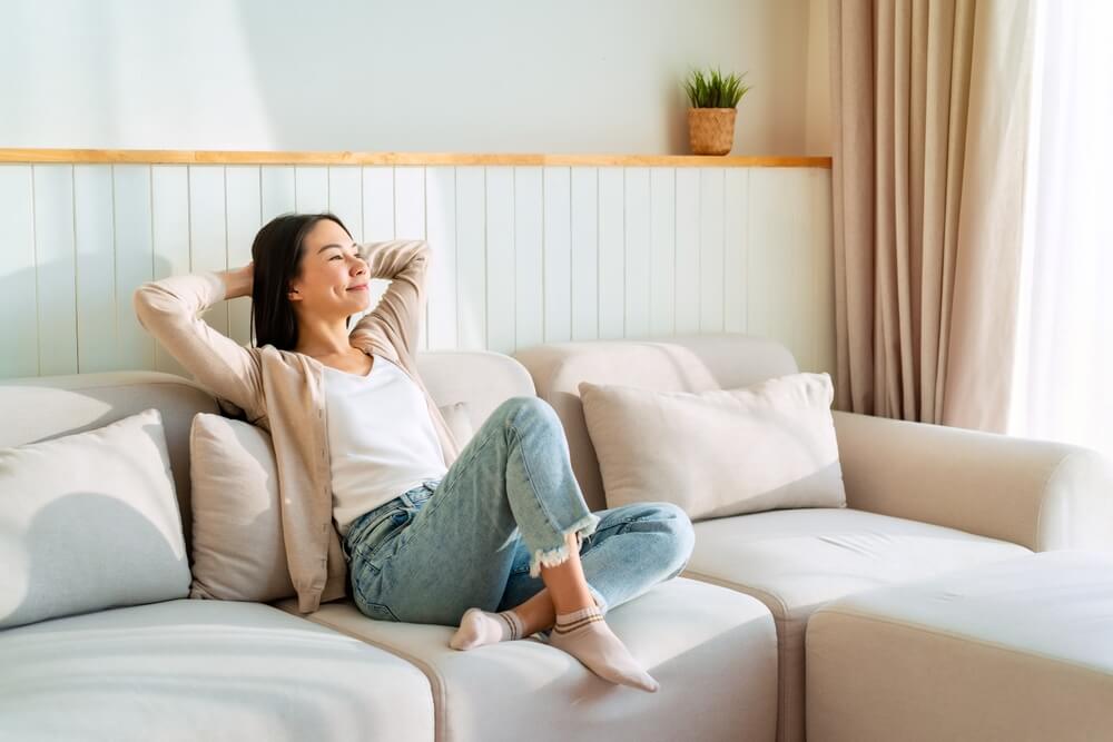 Carefree woman relaxing and sitting on a sofa at home in the morning