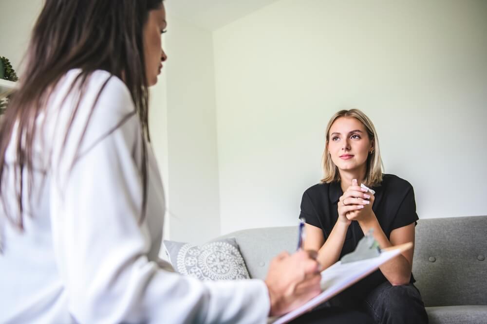 A Psychotherapist supporting depressed teenage girl during appointment in office