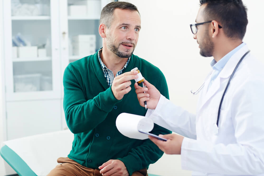 Modern clinician giving bottle with pills to his patient during appointment